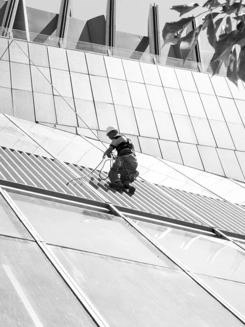 A person in personal protective equipment vacuuming indoors, ensuring a thorough clean.