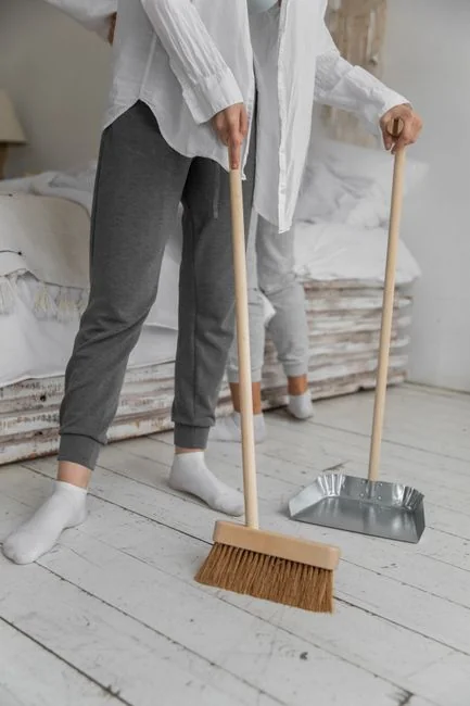 Gray mop leaning against a textured wall, conveying simplicity in a domestic setting.